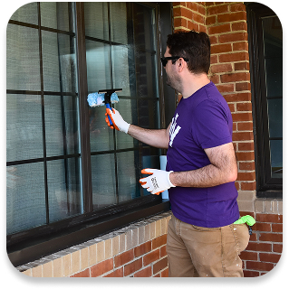 an Ally employee cleaning a window.